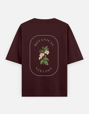 Oversized t-shirt with a vintage botanical illustration of flowers and leaves, framed by elegant arched text reading “Botanical Vintage” on a black background.