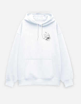 Oversized white hoodie with a small left-chest cracked skull graphic in distressed monochrome style.