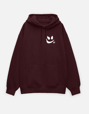 Maroon oversized hoodie with a small front-left white smirk face and tiny “boo” text as a minimalist chest graphic.
