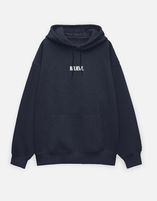 Oversized black hoodie with a small center-chest embroidered text reading “BELIEVE.”