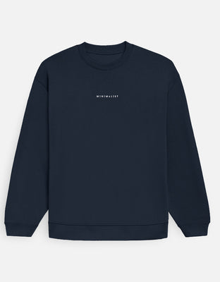 Oversized white sweatshirt with small center-chest “MINIMALIST” wordmark embroidered in black.